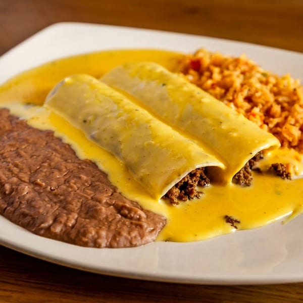 Two beef enchiladas covered in yellow cheese sauce, with refried beans and rice on a white plate.