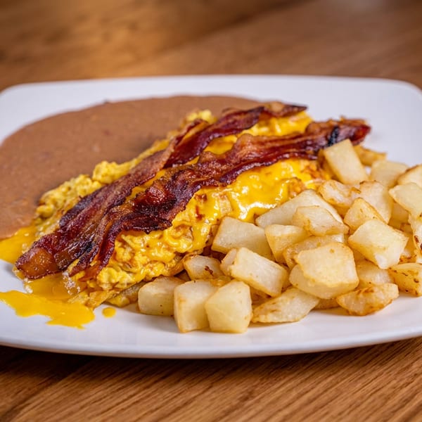 Scrambled eggs with melted cheese and bacon, served with home fries and refried beans.