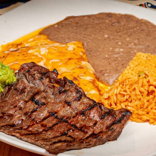 Grilled steak, guacamole, enchiladas, refried beans, and rice on a white plate.